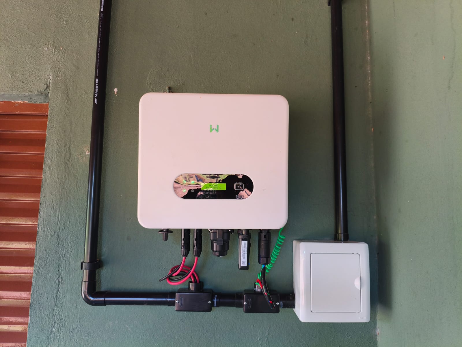 Inversor solar instalado em parede verde com eletrodutos e quadro elétrico